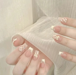 Detailed view of long square press-on nails with French pearls and cream bow designs