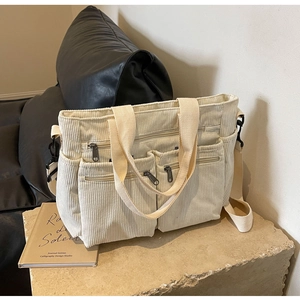 Detail view of beige corduroy tote bag with multiple pockets and woven handles