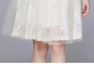 Detailed close-up of white floral lace texture and layered mesh hem on a vintage dress