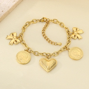 Detail of 18K gold plated bracelet with heart, bow, and coin charms on beige surface