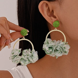 Detail of floral fabric petals and green woven bead on a gold hoop earring for women
