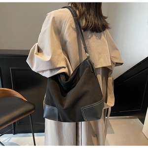 Detail of black frosted tote bag with white stitching on adjustable shoulder strap