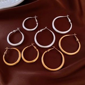 Dettaglio di orecchini a cerchio in oro 18k e argento con finitura spazzolata su seta