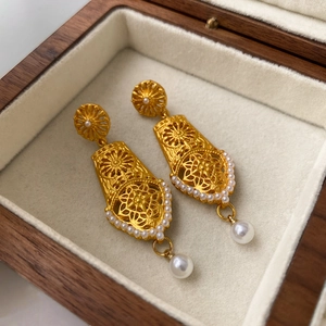 Detail of vintage hollow flower earrings with gold plating and hanging white pearls