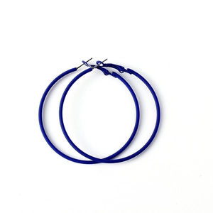Gros plan de boucles d'oreilles créoles bleues en métal laqué effet gomme mat