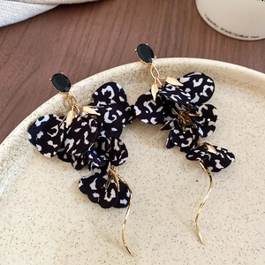 Detail of leopard print fabric flower earrings with long gold tassel and black gemstone