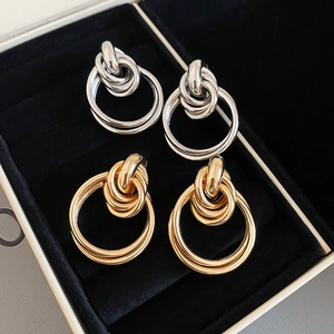 Détails de boucles d'oreilles en nœuds dorés et argentés sur une boîte à bijoux en velours