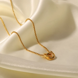 Polished gold double interlocking ring pendant necklace on white draped silk fabric