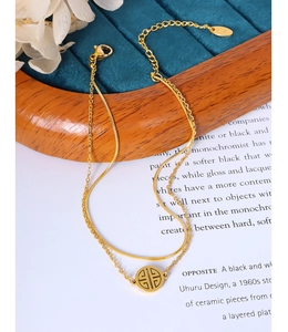 Macro detail of gold double-layered necklace with hollow round pendant on blue velvet