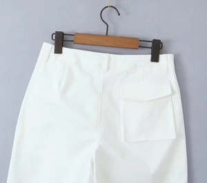 Detail view of white twill cotton cargo pants featuring waistline and large flap pockets