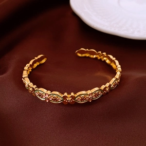 Macro detail of 18k gold plated bangle featuring floral enamel and hollow carving