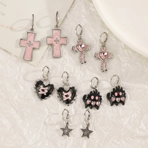 Close-up of mixed Y2K cross and heart earrings set with pink crystals and silver finish