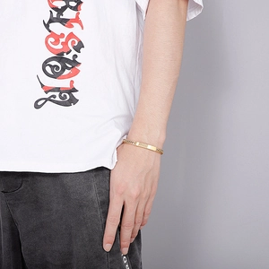 Detail of gold flat chain bracelet with rectangular plaque on male wrist