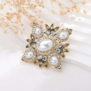 Close-up of a vintage baroque gold brooch with white pearls and sparkling crystals