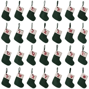 Green knitted Christmas stocking with white cuff and red embroidered alphabet letters