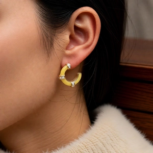 Detail of yellow enamel bamboo-shaped C-earrings with sparkling zircons on a model