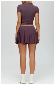 Rear view detail of pleated athletic skirt and slim-fit purple yoga top for women