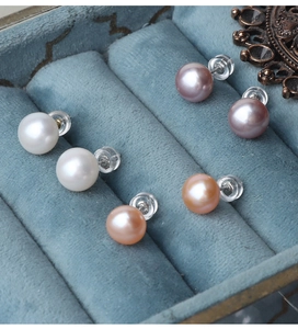 Detailed view of three pairs of round freshwater pearl earrings in white, pink, and orange