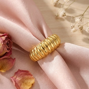 Macro view of a gold croissant ring featuring a spiral texture on pink silk fabric