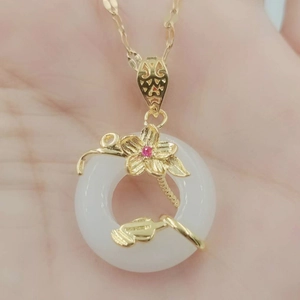 Vue macro d'un ornement floral doré avec pierre rose sur un pendentif en pierre blanche