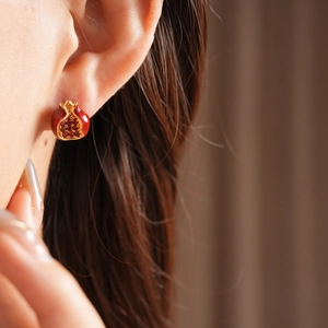 Detail von Vintage-Granatapfel-Ohrringen mit roter Emaille und Zirkonia an einem Model