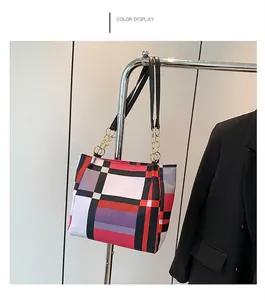 Dettaglio borsa tote geometrica a blocchi di colore con catena dorata su espositore