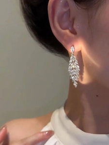 Long silver tassel earrings with zircon leaf design worn by a female model on ear