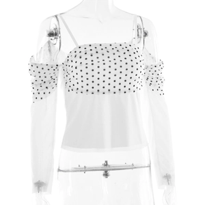 Detail view of semi-transparent polka dot mesh sleeves on a white off-shoulder top