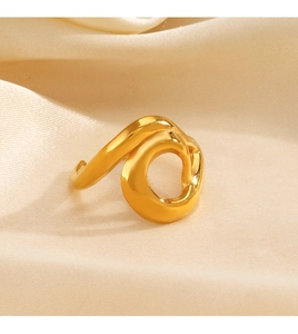 Gros plan d'une bague dorée irrégulière ajourée posée sur un tissu en soie champagne
