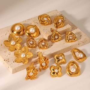 Vintage gold pearl earring set with floral and geometric designs on a stone display