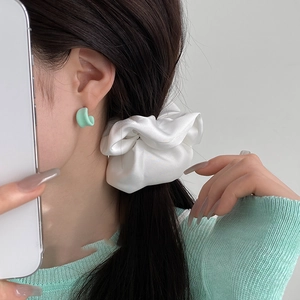 Minimalist white satin oversized scrunchie worn by a model in a clean lifestyle shot