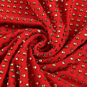 Macro detail of red knitted fabric with dense sparkling gold rhinestone embellishments