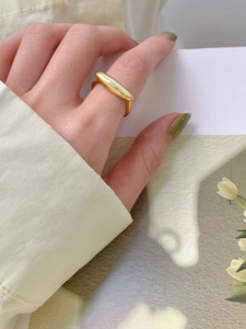 Anello geometrico dorato minimalista indossato al dito con elegante dettaglio floreale