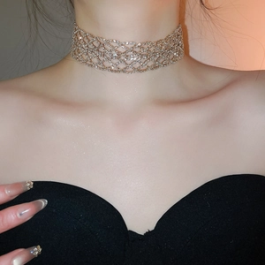 Vue rapprochée d'un ras-du-cou à mailles évidées orné de strass dorés couleur champagne