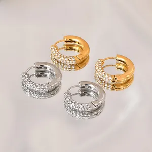 Macro shot of gold and silver hoop earrings with micro-pave cubic zirconia on reflective surface