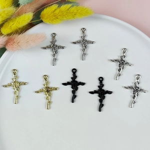 Trois pendentifs croix rose en or, argent et noir sur une assiette blanche