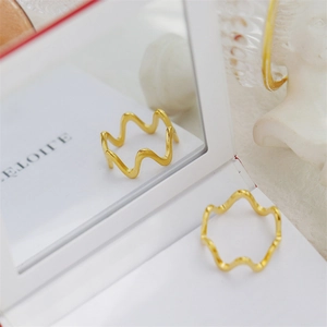 Detail shot of wavy 18K gold plated ring with elegant gear texture on mirror reflection