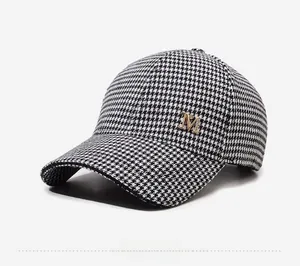 Gros plan détaillé d'une casquette pied-de-poule avec logo M doré serti de strass