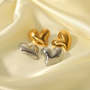 Détail de boucles d'oreilles en forme de cœur polies or et argent sur du satin