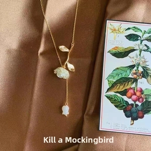 Detailed view of a gold rose necklace with white petals on silk background