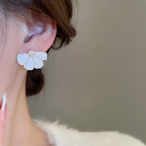 Détail d'un clou d'oreille fleur blanche avec centre doré porté sur l'oreille