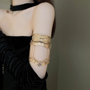 Detail of vintage gold layered arm cuff featuring metal coins and fringe chains decoration