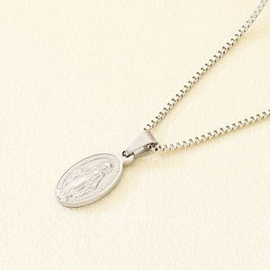 Macro detail of oval Virgin Mary relief pendant on a durable stainless steel box chain