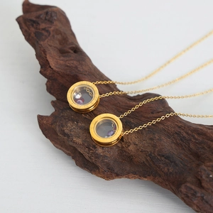 Elegant gold titanium steel necklace with Roman numeral pendant on driftwood