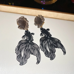 Detail view of black hollow goldfish drop earrings with smoke gray resin flower accents