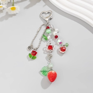 Portachiavi fragola con nappa di perline e chiusura a cuore su sfondo minimalista
