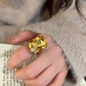 Detailed close-up of a luxury square yellow crystal ring on a model's finger
