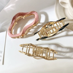 Three large metal claw clips in pink, black, and gold with irregular line designs