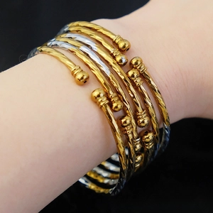 Close-up of stacked gold and silver bangles with hammer texture on wrist with dark background