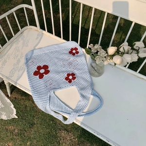Detail der hellblauen Stricktasche mit roten Blumen auf einer weißen Gartenbank